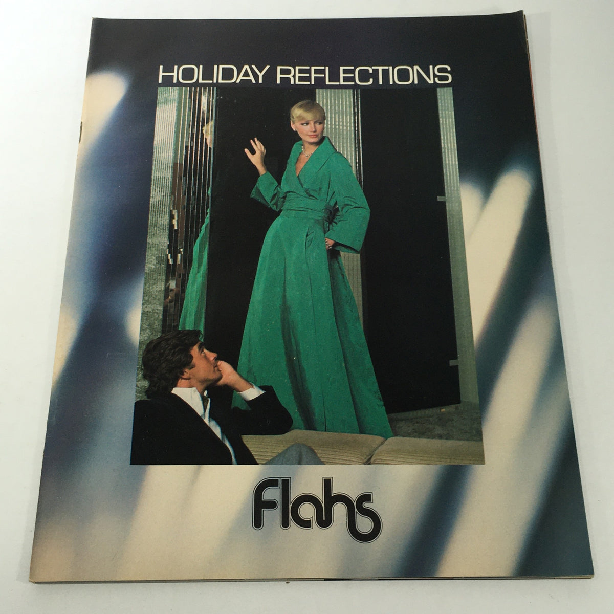 VTG Flahs Catalog: December 1970s - Holiday Reflections cover featuring a model in a green gown with a modern aesthetic, alongside a man in formal attire gazing thoughtfully.