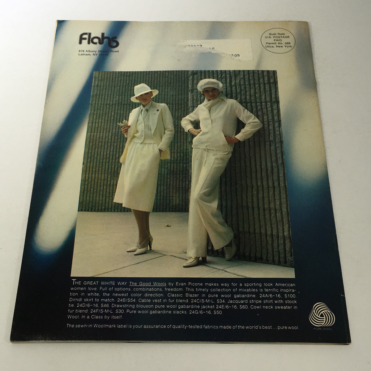 VTG Flahs Catalog: December 1970s - Holiday Reflections featuring two stylish women dressed in coordinating white outfits, including a hat and skirt, with a modern architectural background highlighting 1970s fashion trends.