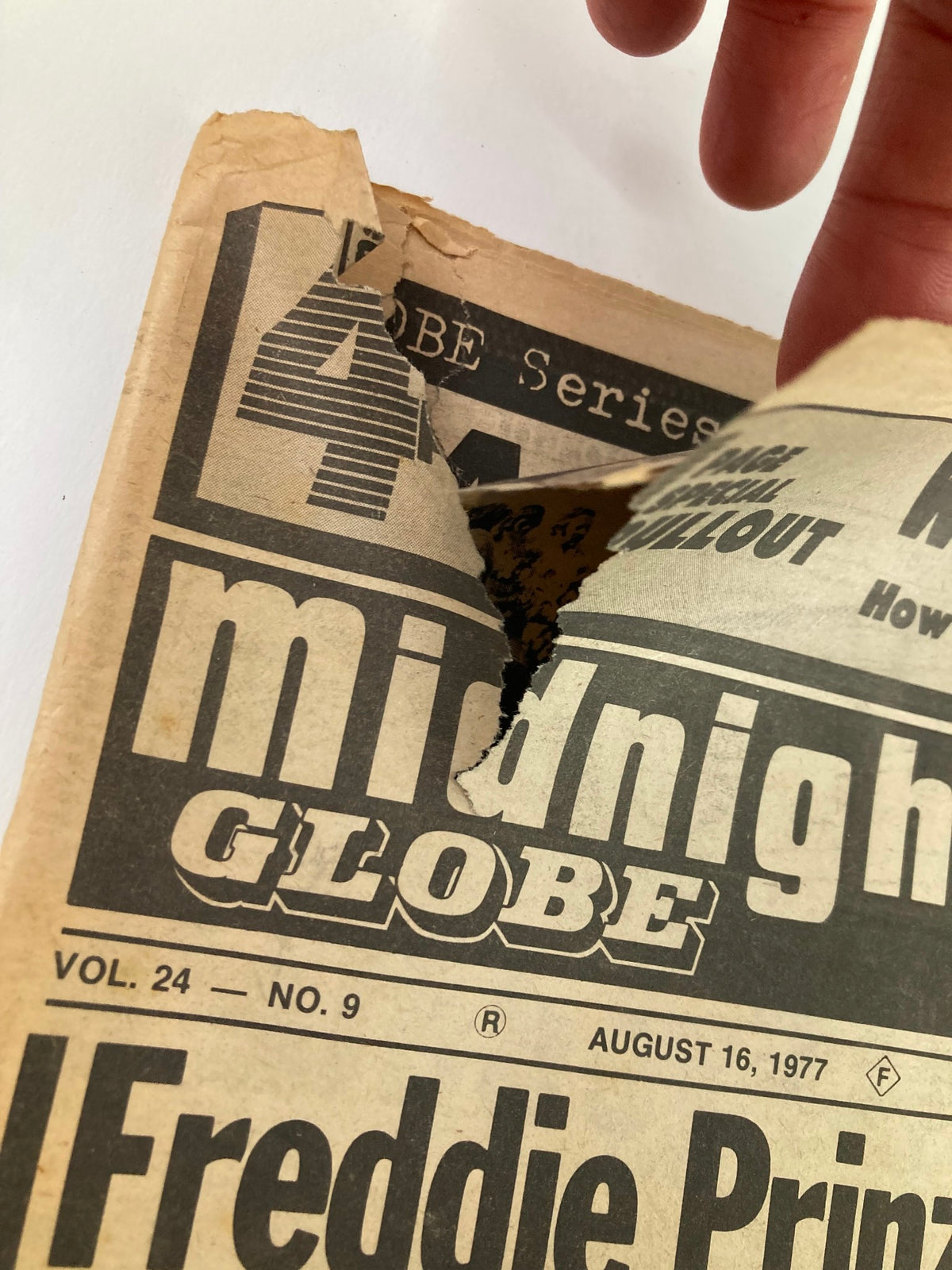 Close-up of the corner of the Midnight Globe Tabloid August 16 1977 Vol 24 #9, showing a tear on the cover, illustrating the wear and condition of this vintage publication.