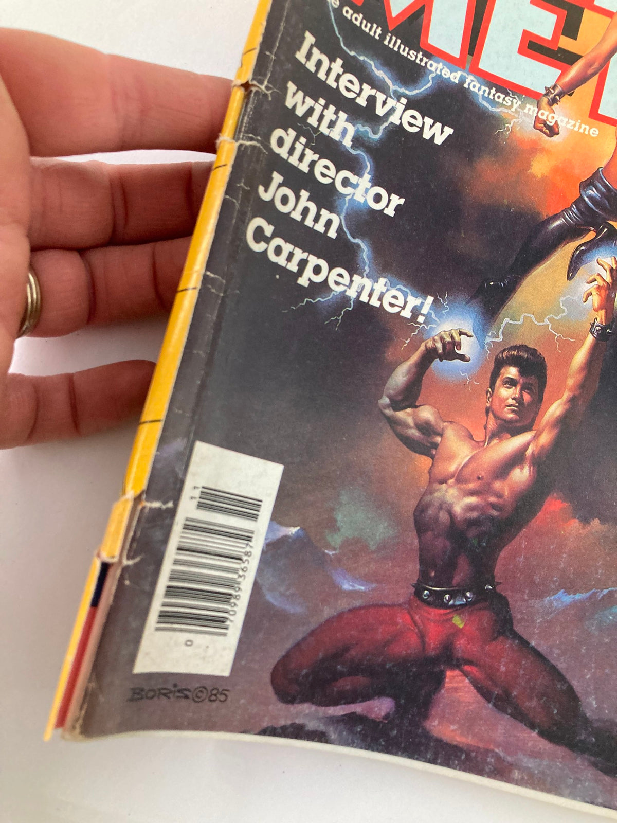 Side view of the VTG Heavy Metal Magazine November 1985 Vol 9 #8 showing creases and details of the cover art featuring a muscular man and woman.