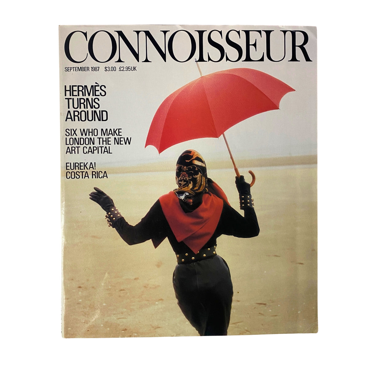 Cover of Connoisseur Magazine, September 1987, featuring the article 'Hermès Turns Around.' The image shows a model in a stylish outfit holding a red umbrella against a beach background, showcasing themes of luxury and fashion.
