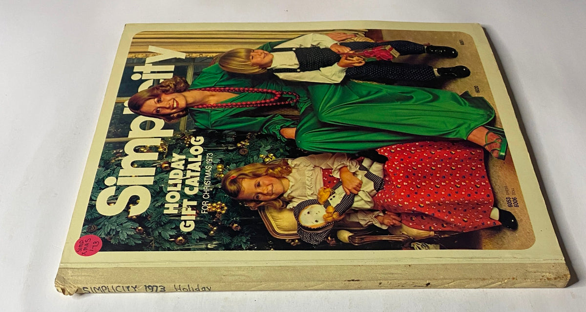 Cover of the 1973 Simplicity Holiday Gift Catalog displaying a woman in a green dress with children, ideal for Christmas sewing inspiration and holiday fashions.