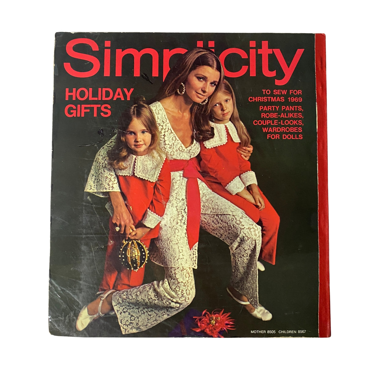 1969 Simplicity Holiday Catalog sewing pattern cover featuring a woman in a white dress surrounded by two girls in red outfits, showcasing holiday gifts and festive sewing ideas.