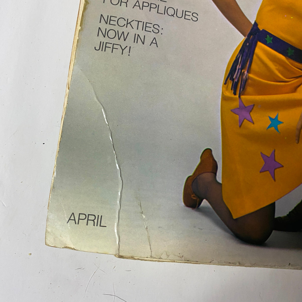 Close-up of the 1971 April Simplicity Spring Catalog, focusing on the cover text highlighting quick sewing projects like neckties, showcasing the era's distinctive fashion trends.