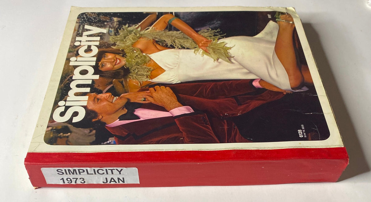 Side view of the 1973 January Simplicity Catalog, highlighting the stylish cover design. The catalog contains sewing patterns for various fashion styles, including men's and women's evening wear for elegant occasions.