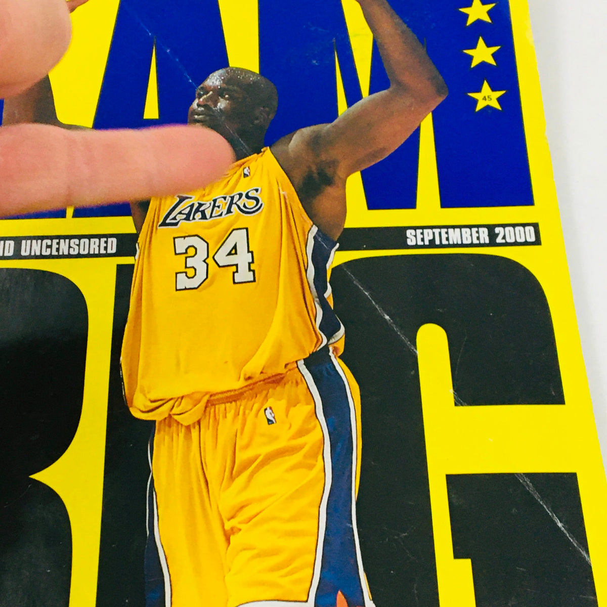 Close-up of Slam Magazine September 2000 cover featuring Shaquille O'Neal in LA Lakers jersey number 34, emphasizing his victory stance.