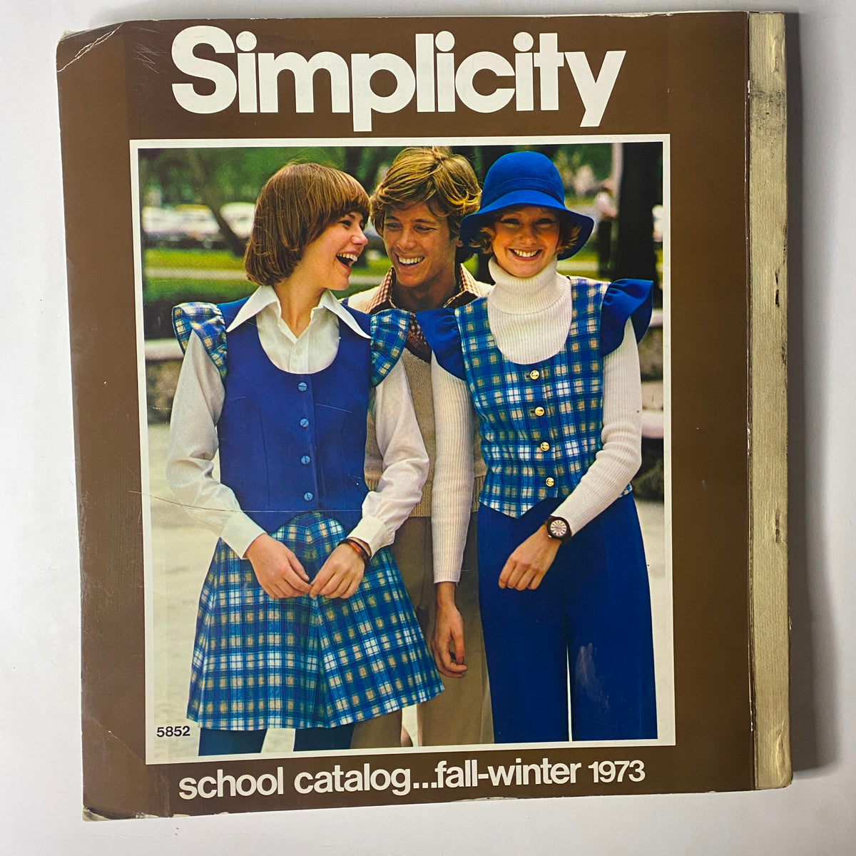 Cover of the 1973 Simplicity Fall and Winter School Catalog showing three smiling models wearing coordinated outfits, emphasizing classic styles and school fashion.