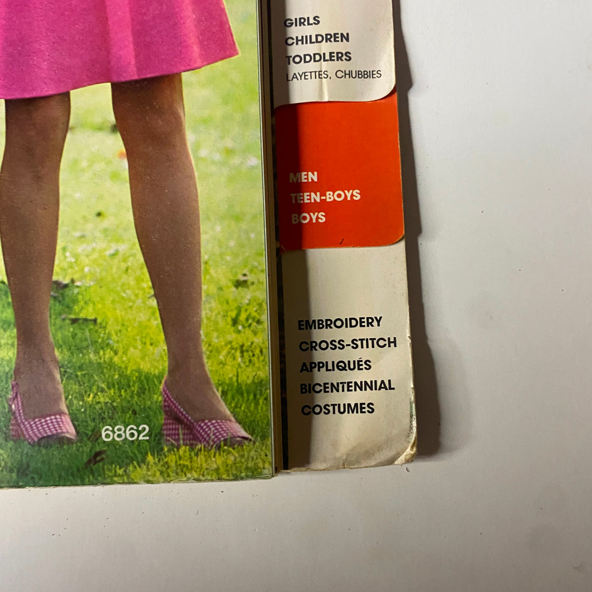 Detailed view of the 1975 Simplicity Special Catalog outlining options for boys and girls clothing alongside sewing patterns for embroidery and cross-stitch.