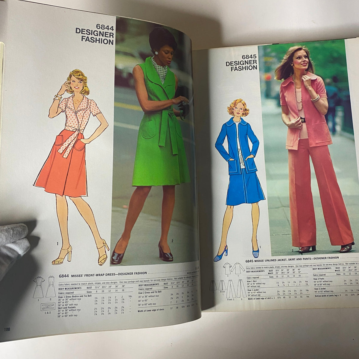 Designer fashion highlights from the 1975 April Simplicity Catalog featuring stylish dresses and coordinated sets for women. Designs include a front wrap dress and chic ensembles.
