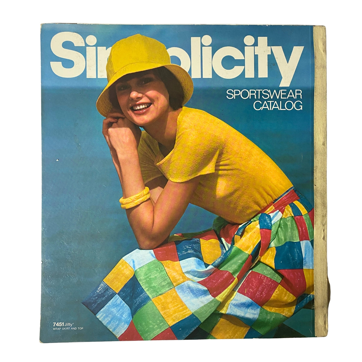 Cover of the 1976 Simplicity Sportswear Catalog featuring a model in a yellow outfit and colorful skirt, showcasing bold summer fashion styles of the 1970s.