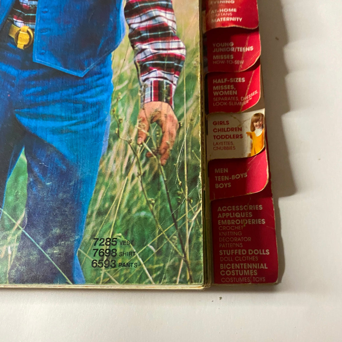 Detailed view of the 1976 October Simplicity Sewing Pattern Catalog emphasizing the plaid designs along with various category tabs for sewing patterns.