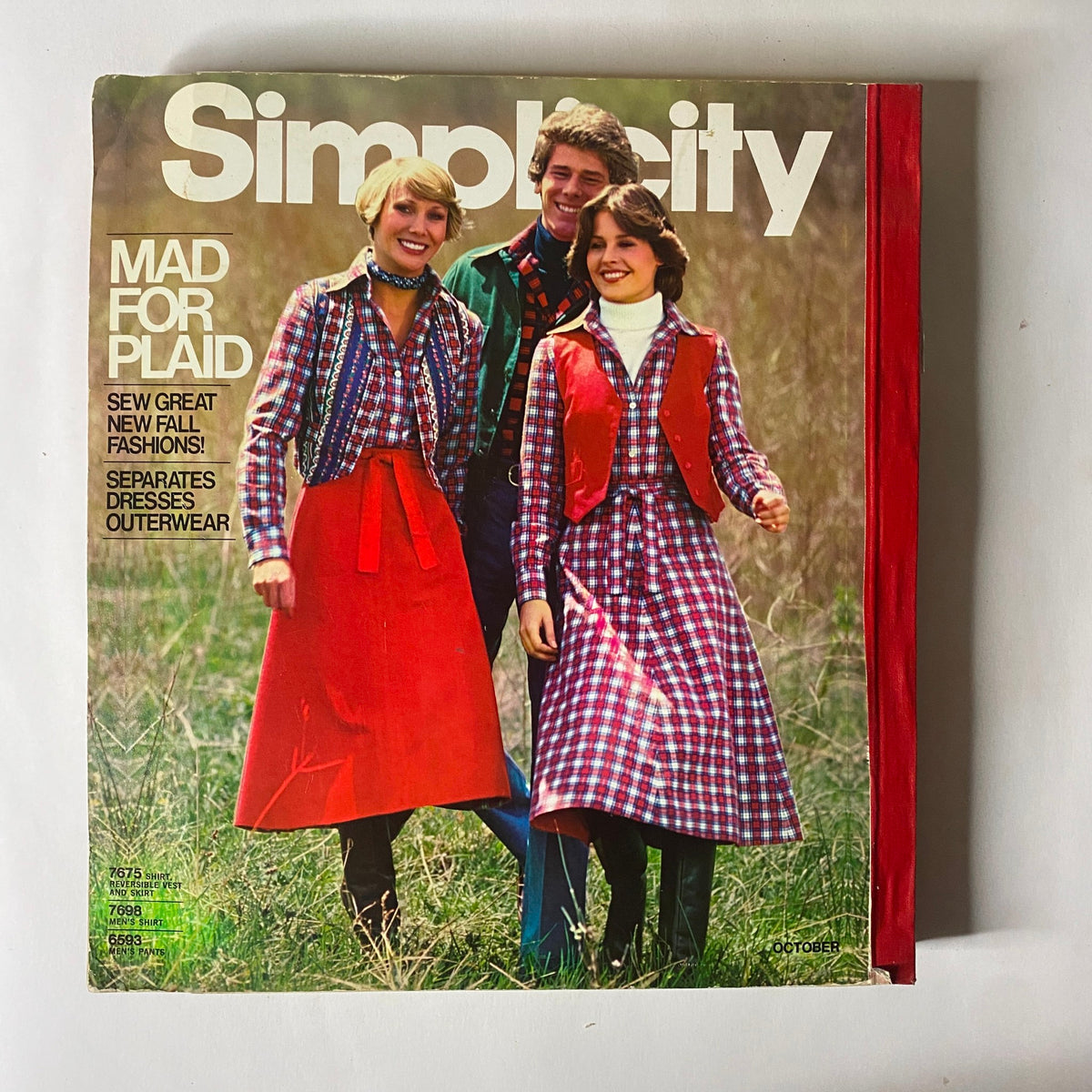 Cover of the 1976 October Simplicity Sewing Pattern Catalog titled 'Mad for Plaid', displaying a group of three models in plaid outfits, showcasing popular fall fashion trends.