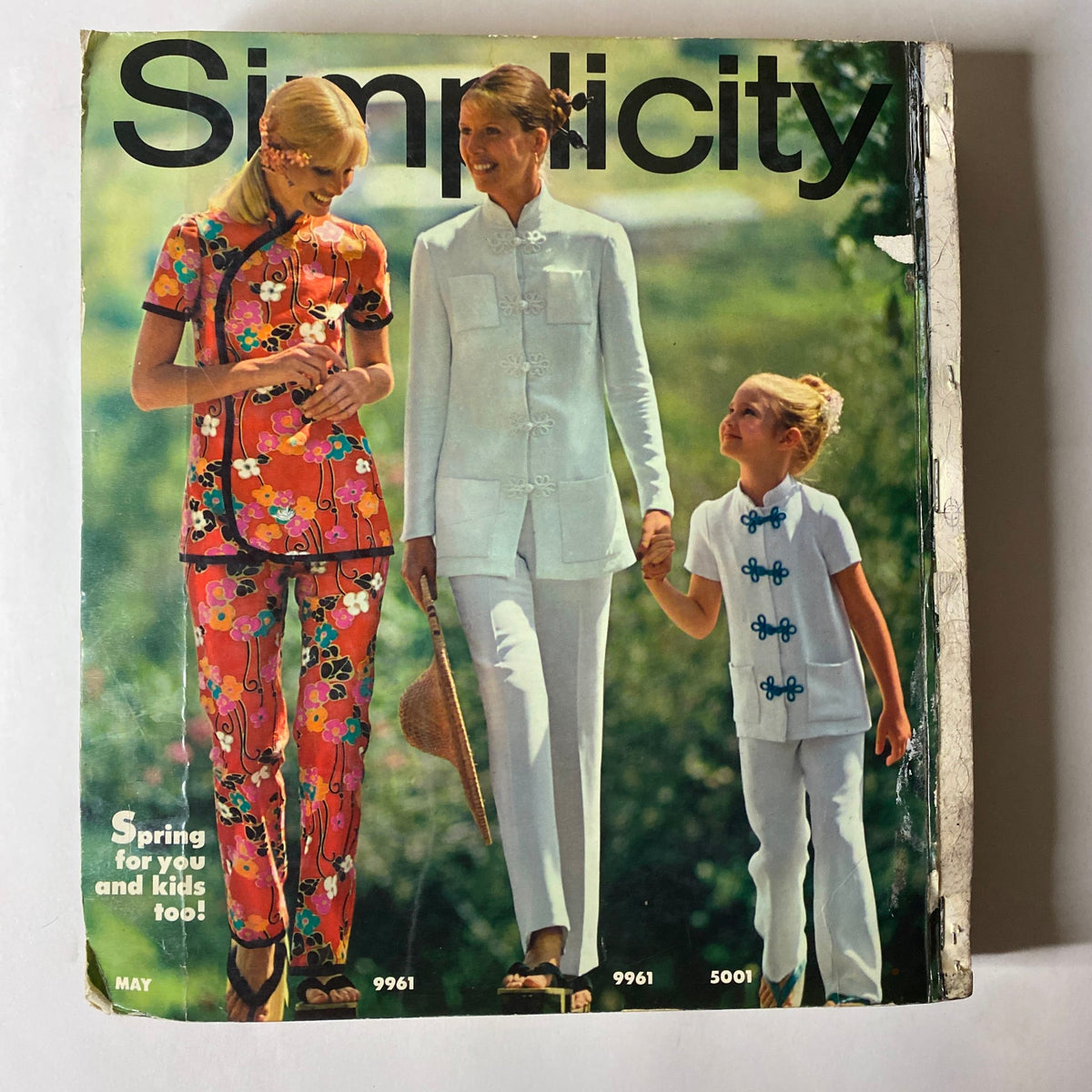1970s May Simplicity Sewing Pattern Catalog cover illustrating vintage spring fashions for mothers and children, showcasing bright colors and unique styles.