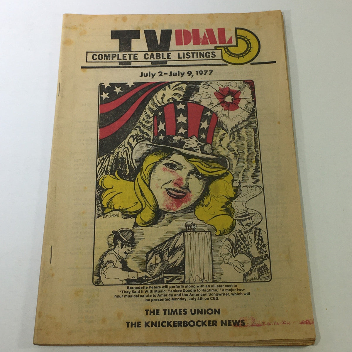 VTG TV Dial Complete Cable Listings July 2-9 1977 featuring a vibrant cover illustration with a patriotic theme and Bernadette Peters performance announcement.