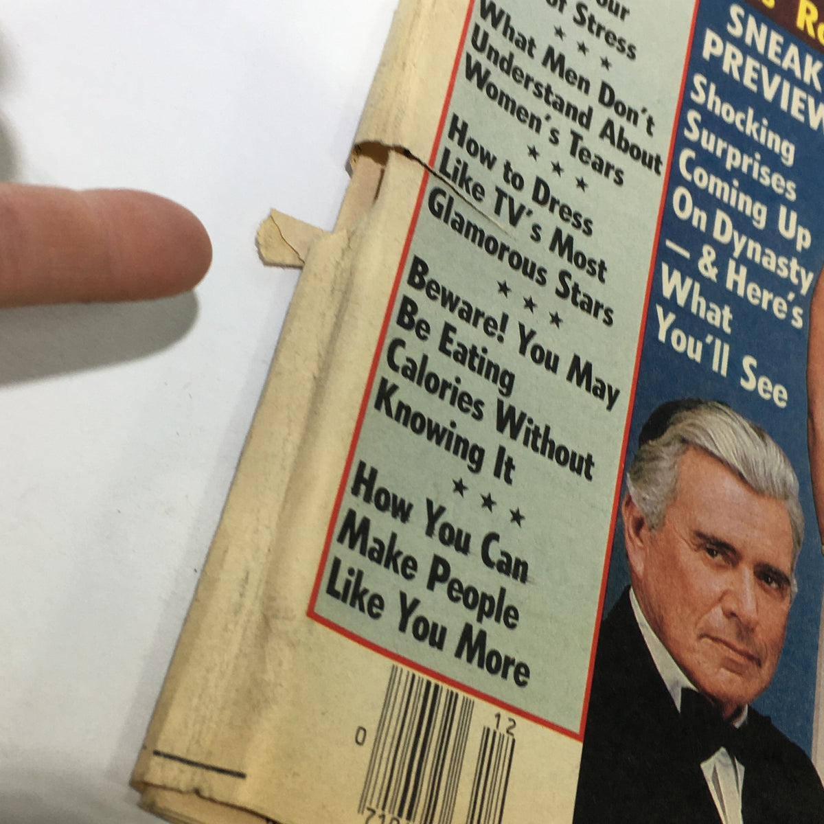 Close-up detail of the side panel of the National Enquirer Magazine, highlighting articles about celebrity culture and includes a prominent photo and caption.