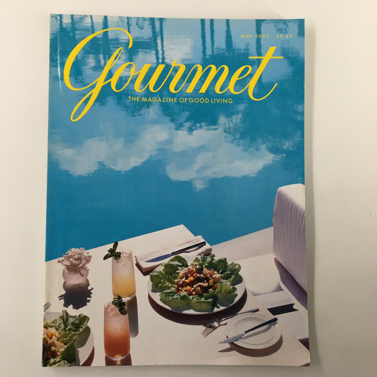 Cover of Gourmet Magazine May 2002 featuring poolside dining at The Shore Club, showcasing beautiful outdoor table settings, refreshing cocktails, and vibrant dishes against a serene, sunny backdrop.