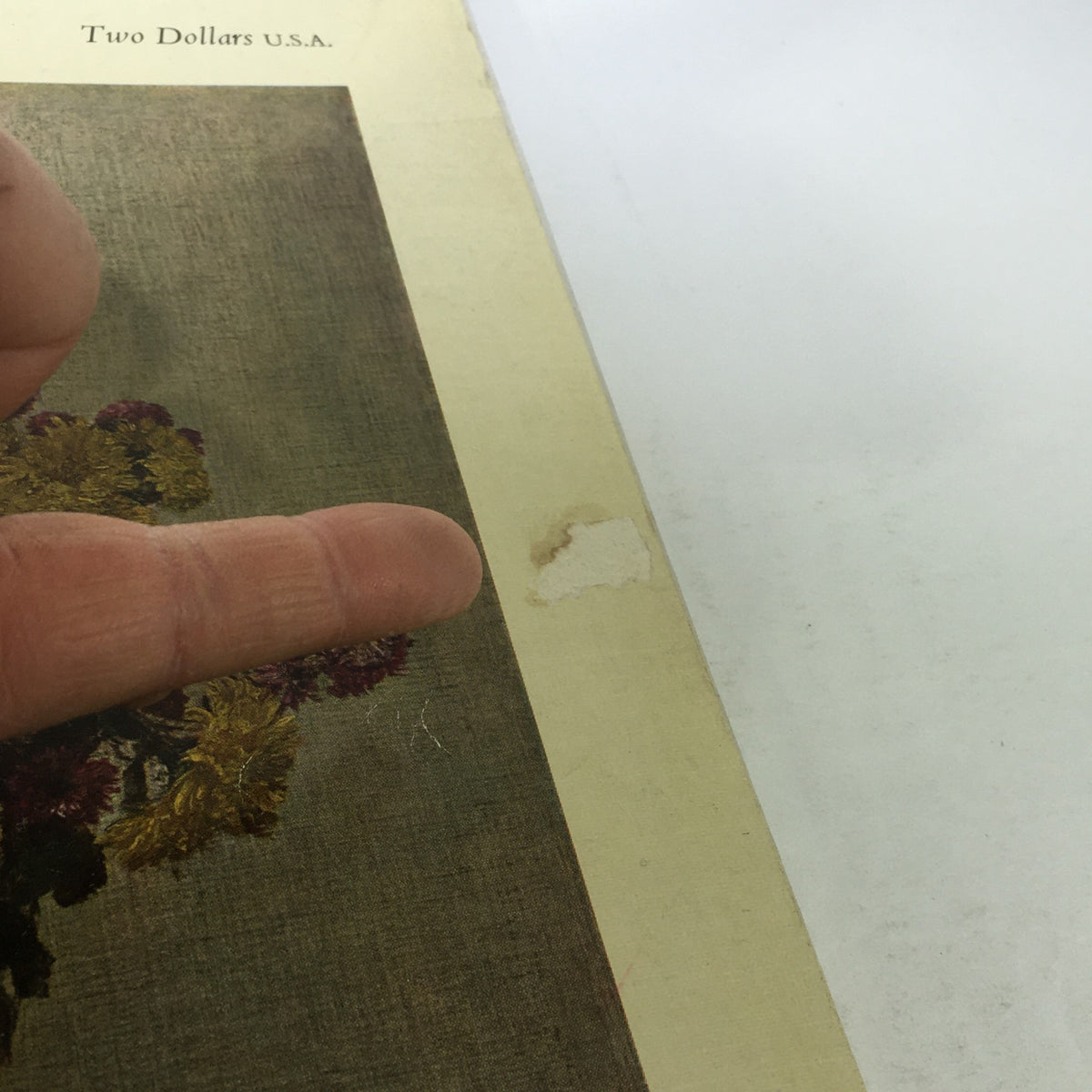Close-up detail of the cover of The Connoisseur magazine, April 1962, indicating signs of wear with a finger pointing to a mark, illustrating the vintage condition.