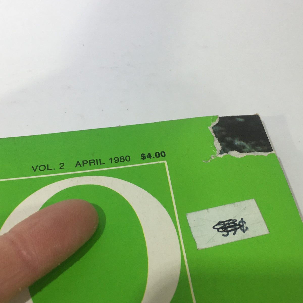 Close-up of the corner of VTG Geo Magazine: April 1980 Vol. 2 showing the title and price sticker. The magazine displays wear at the top right corner.