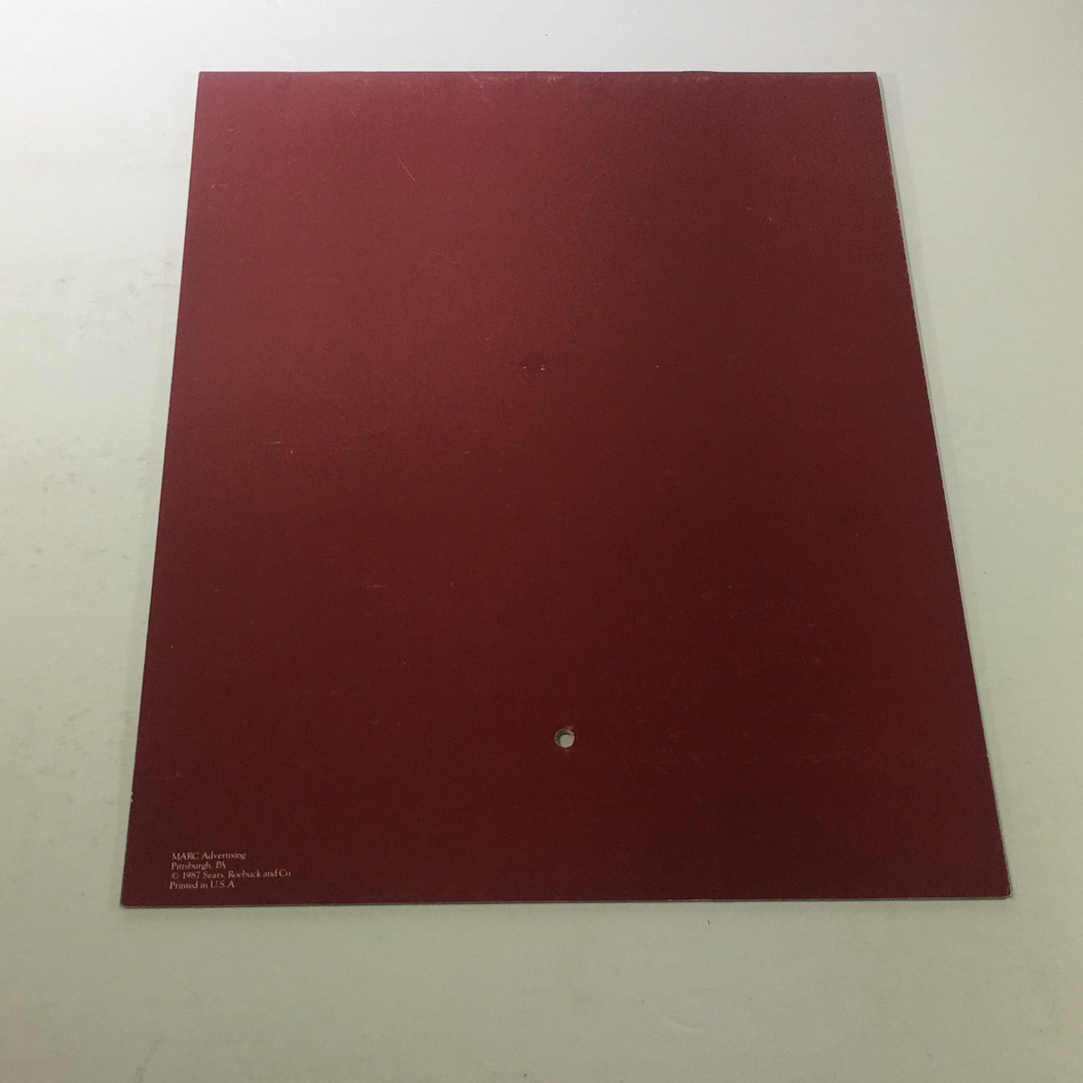 The back cover of the VTG Sears 1988 Classic Calendar Consumer Guide, displayed in a solid red color with a small hole at the center.