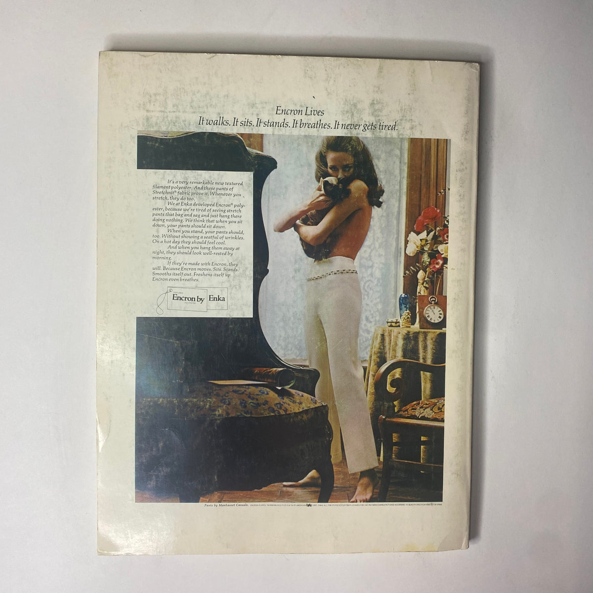 Back cover of the 1968 American Fabrics No. 79 Summer Catalog featuring a model in white pants, holding a black cat. The text reads 'Encron Lives' highlighting fabric qualities. The backdrop includes decorative elements typical of the late 1960s, emphasizing the fashion and textile trends of the era.
