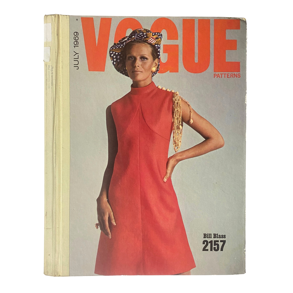 1969 Vogue Patterns July Catalog Large Store Counter Pattern Book featuring a stylish model in a red dress, showcasing late '60s fashion. Cover design includes bold orange text and a chic hat.