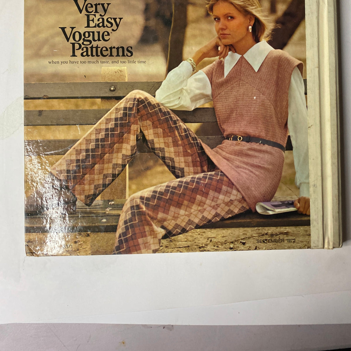 Cover image from the 1972 Vogue Patterns September Catalog featuring a woman in a pink sleeveless tunic and patterned pants, sitting on a park bench, exuding a sophisticated casual look.