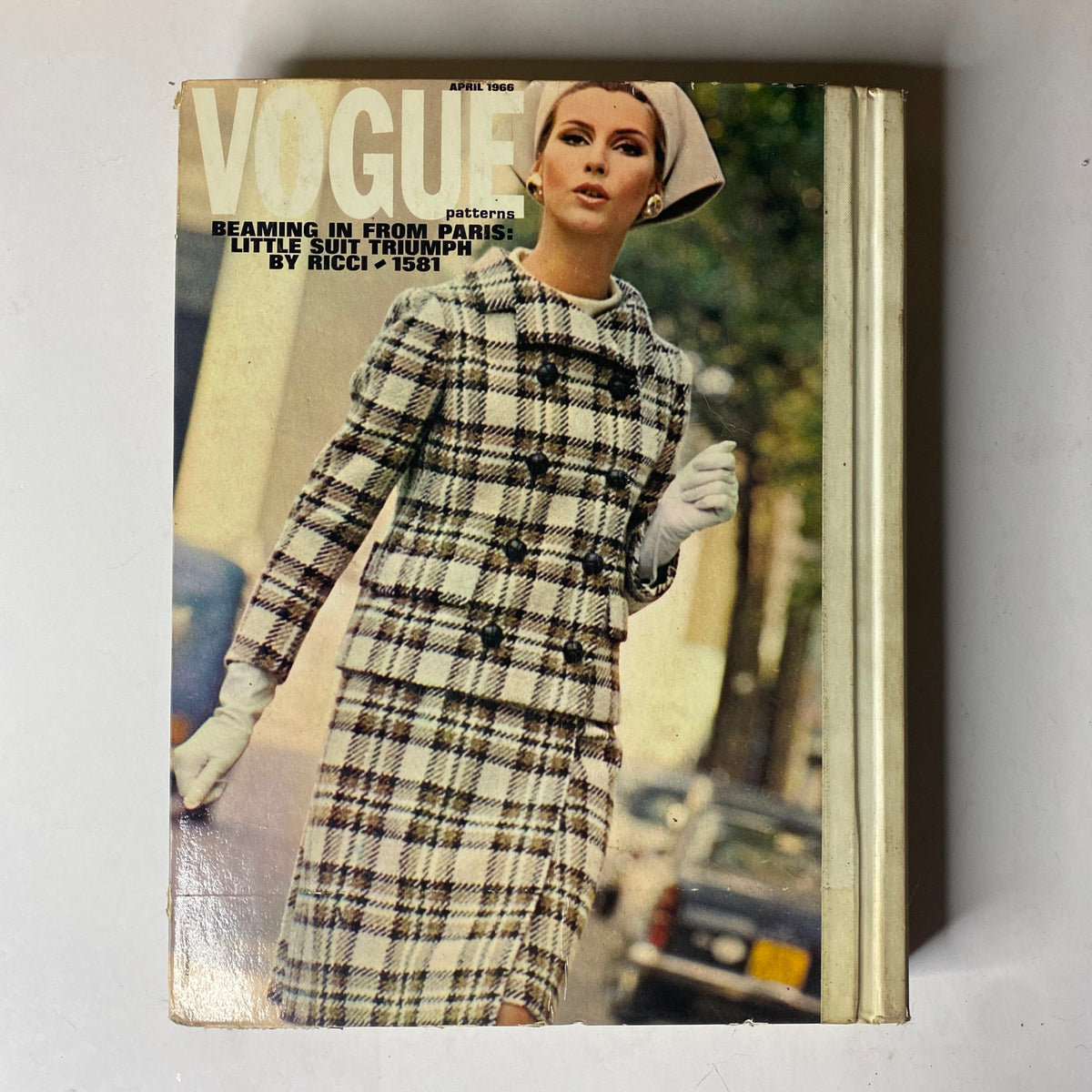 1966 Vogue Patterns April Catalog cover with a model in a chic plaid suit, emphasizing classic elegance in vintage fashion.