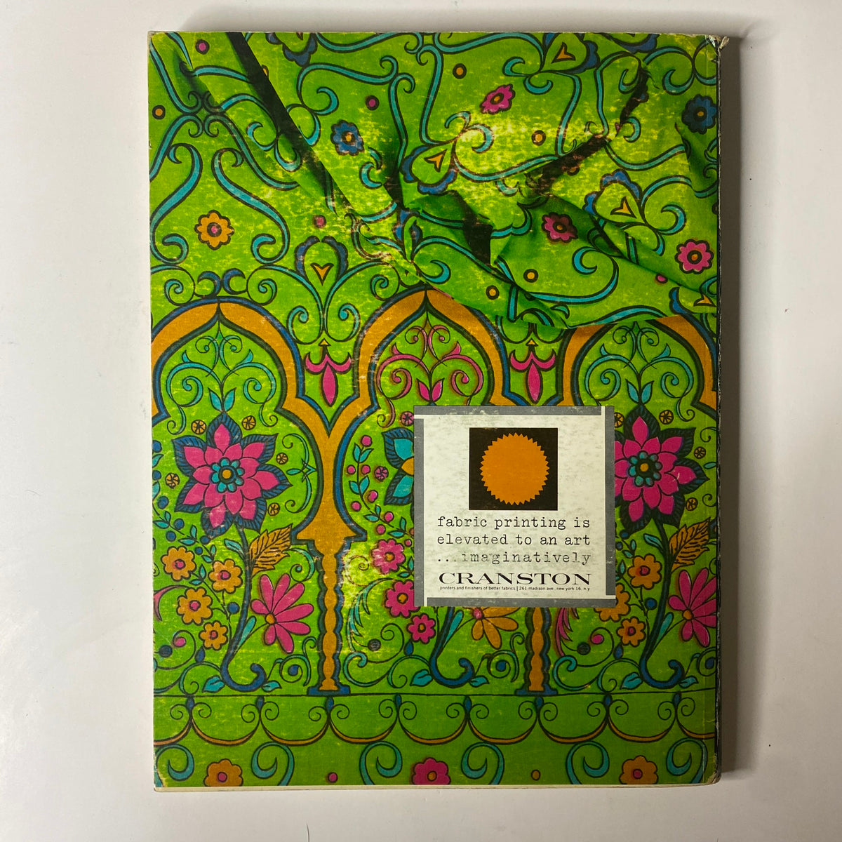 Vibrant cover design of the 1964 American Fabrics No. 64 Summer Catalog featuring floral patterns and intricate motifs in bright colors. The title emphasizes fabric printing as an elevated art form, produced by Cranston.