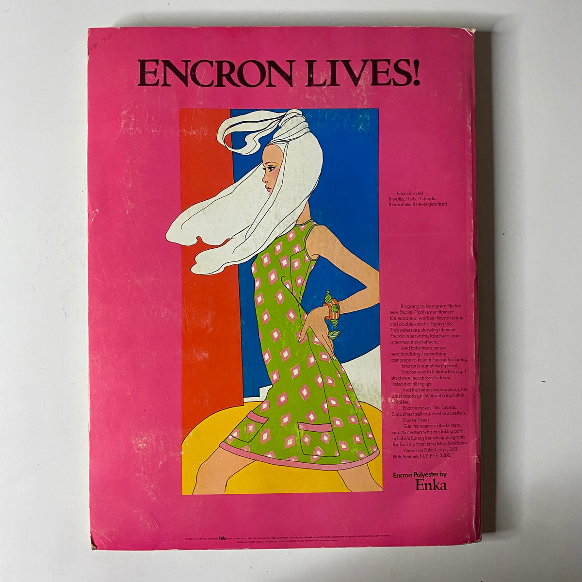 Cover of the 1967 American Fabrics No. 77 Fall-Winter Catalog featuring a vibrant pink background with a fashionable model in a green patterned dress, complete with a white head wrap and holding a decorative item, showcasing textile designs from the late 1960s.