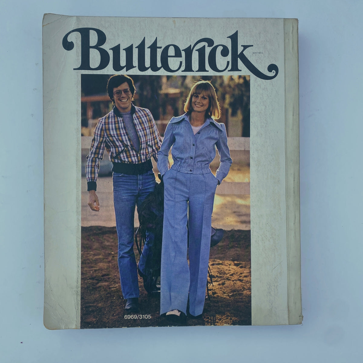 Cover of the 1973 May Butterick Catalog featuring relaxed 1970s fashion styles, including denim outfits for men and women, showcasing nostalgic trends.