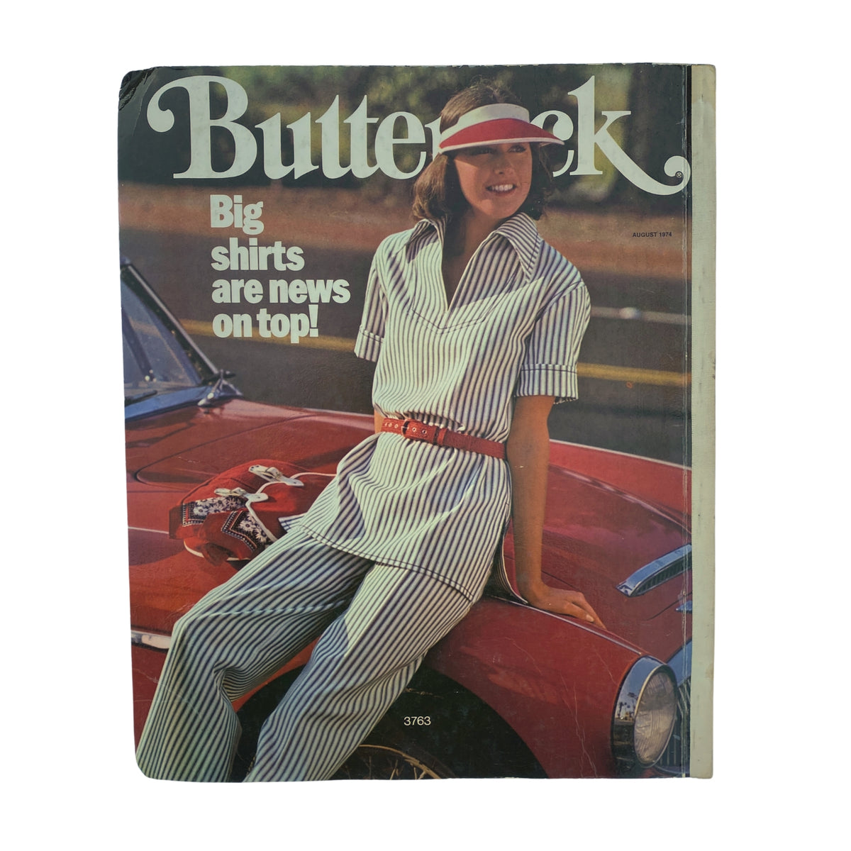 1974 August Butterick Catalog cover displaying a stylish model in a striped outfit, promoting the latest trends in casual wear with the headline 'Big shirts are news on top!'