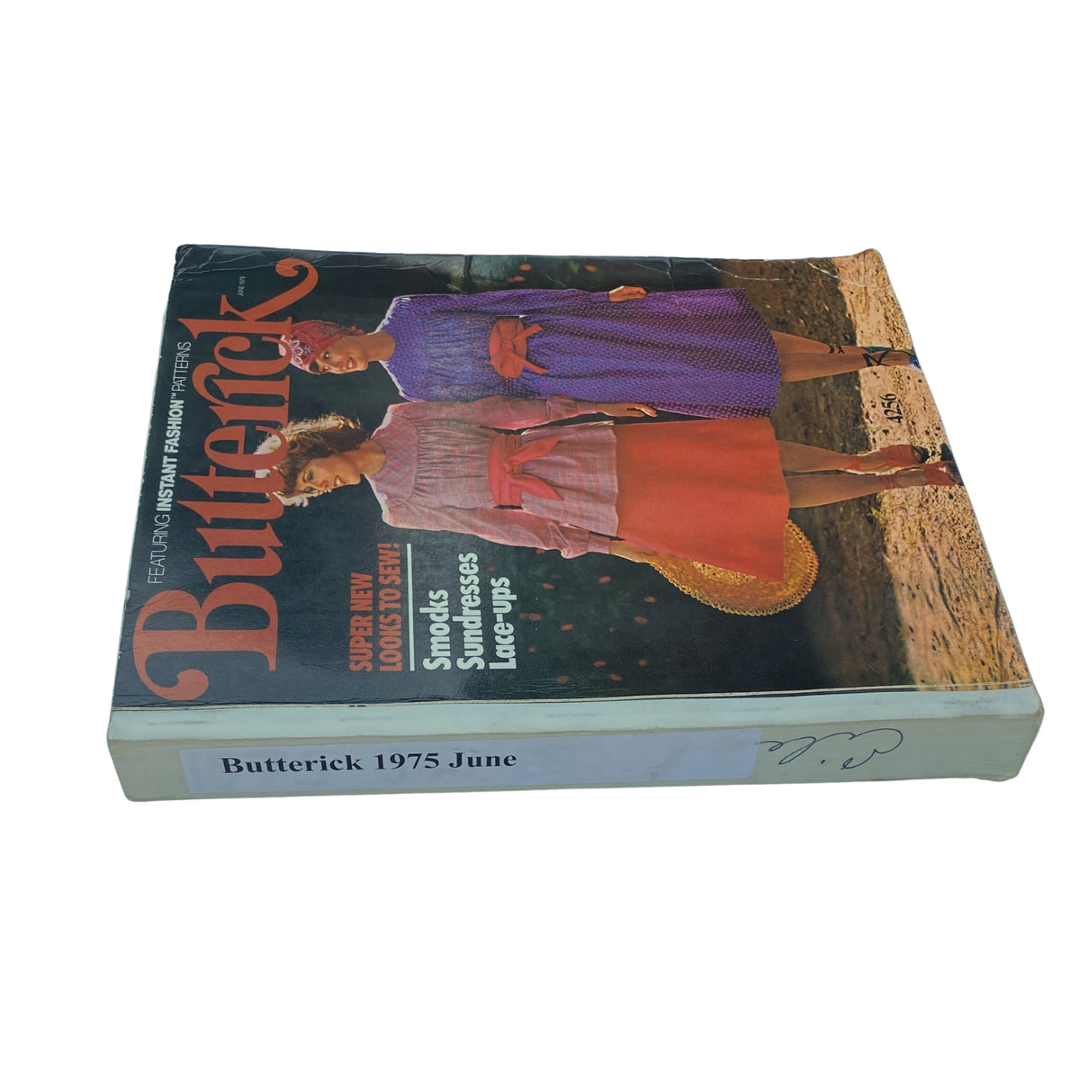 Side view of the 1975 June Butterick Catalog displaying its cover and binding, with emphasis on its vintage sewing patterns for smocks and sundresses.