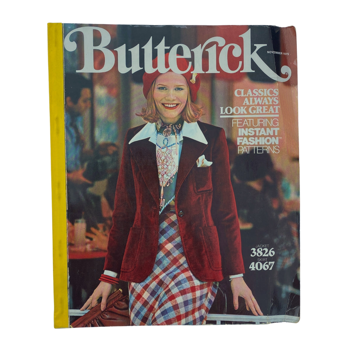 1975 November Butterick Catalog cover showcasing a model wearing a stylish burgundy jacket and plaid skirt, highlighting trends in fall fashion. Features the text 'Classics Always Look Great' and 'Featuring Instant Fashion Patterns'.