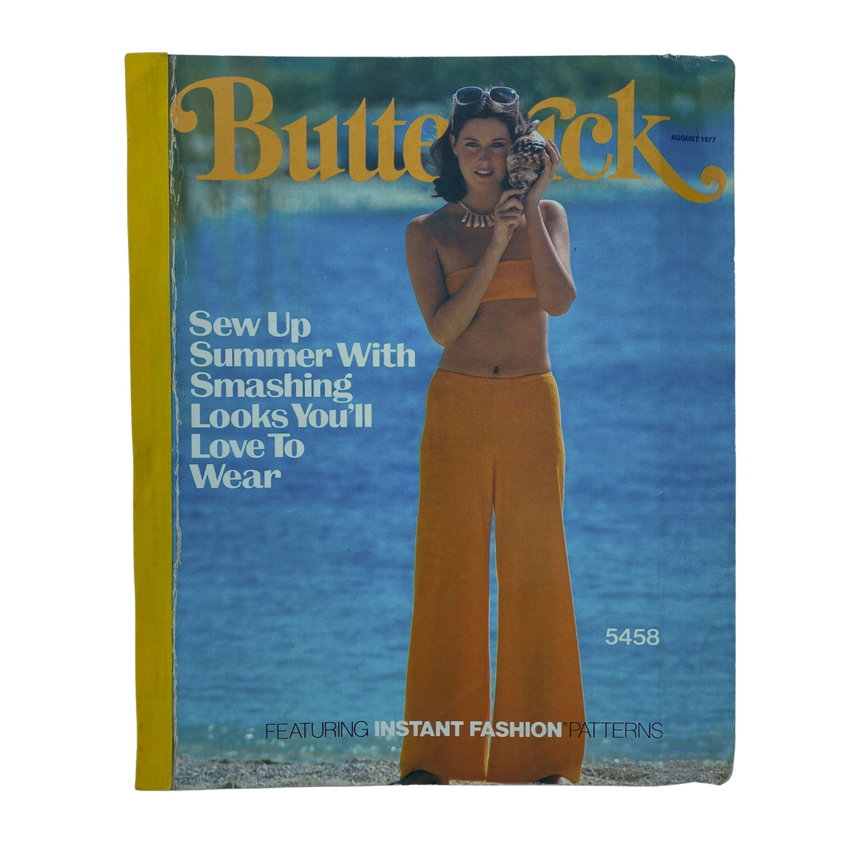 Cover of the 1977 August Butterick Catalog featuring a woman in a stylish orange two-piece outfit, promoting summer fashion and sewing patterns with the slogan "Sew Up Summer With Smashing Looks You'll Love To Wear".