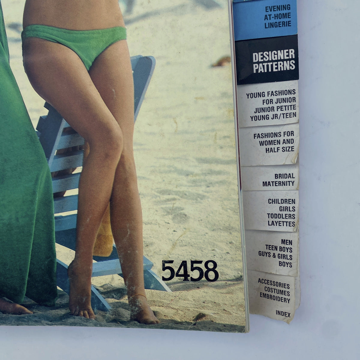 Close-up of the 1977 August Butterick Catalog displaying a model in swimwear and coordinating outfits, featuring a chic green bikini and flowing cover-up.