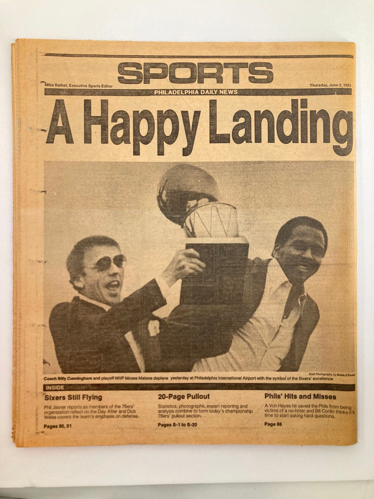 Philadelphia Daily News Tabloid June 2, 1983 highlighting Coach Billy Cunningham and MVP Moses Malone with a trophy at Philadelphia International Airport, celebrating the Sixers' success.