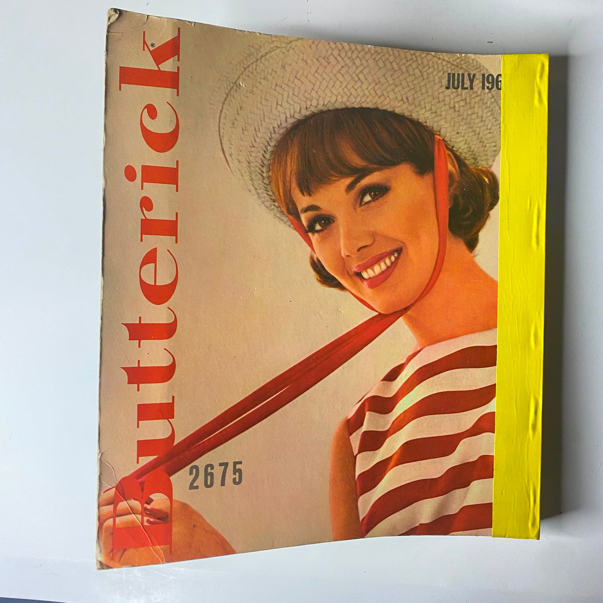 Cover of the 1963 Butterick June Catalog featuring a smiling woman in a striped dress with a sun hat, illustrating classic 1960s summer fashion.