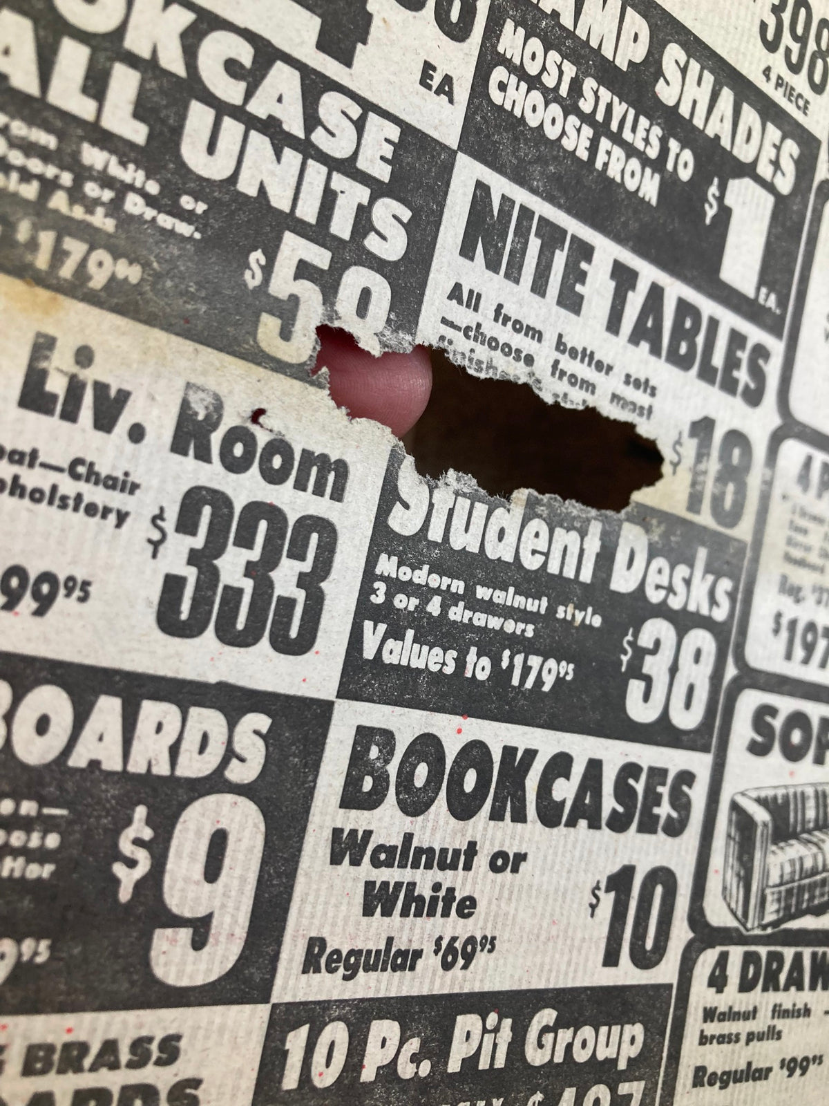 Close-up of a vintage advertisement from the Philadelphia Journal, showcasing various furniture options including student desks and bookcases, with a notable tear.