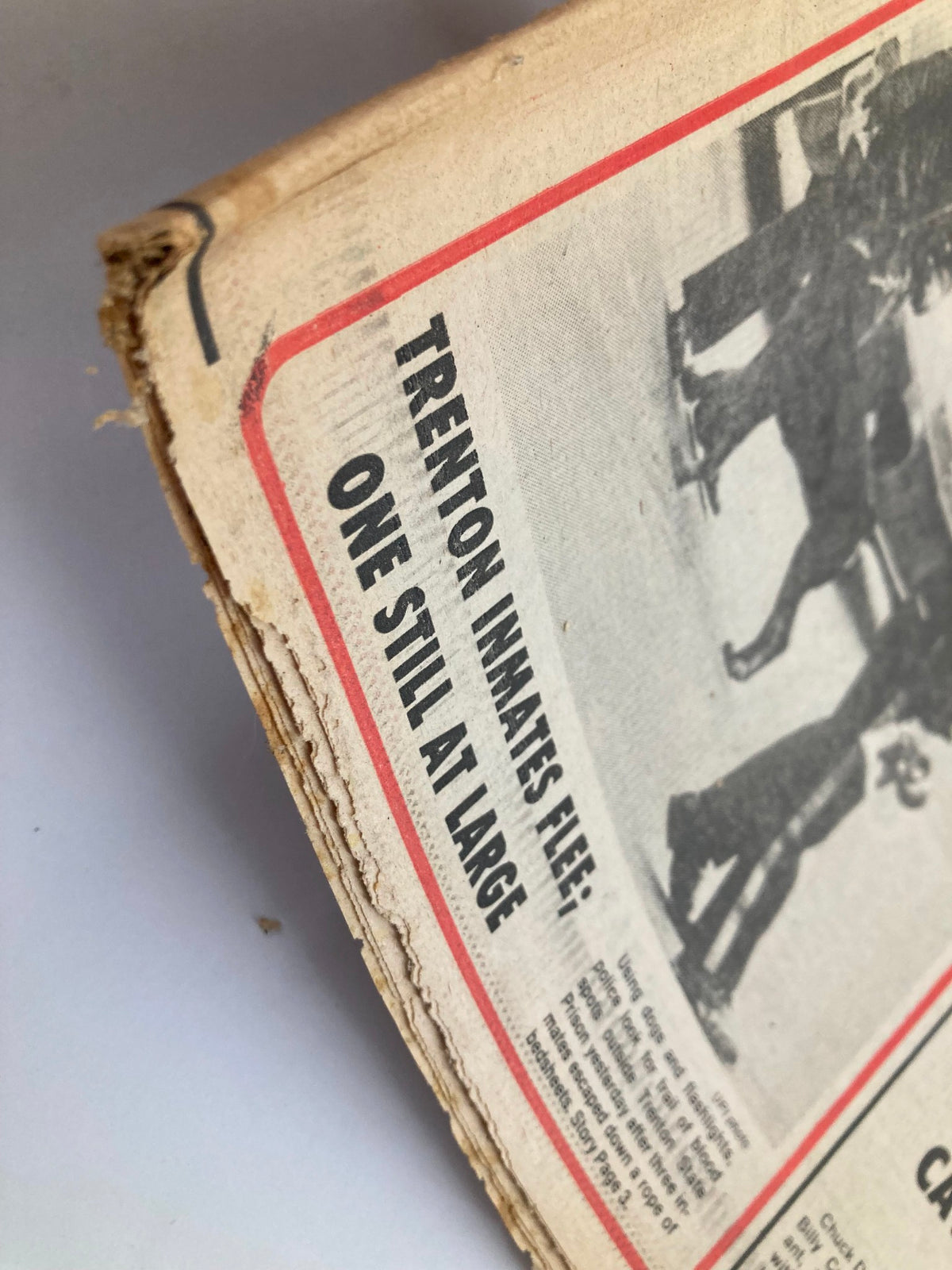 Close-up of the Philadelphia Journal Tabloid detailing the story 'TRENTON INMATES FLEE; ONE STILL AT LARGE' from December 5, 1981. Captures the edge of the newspaper showing wear and the vintage print.