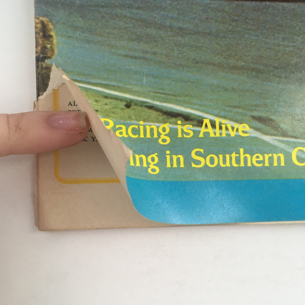 Close-up of Road & Track Magazine February 1969 showing a partially peeled corner with the text 'Racing is Alive' highlighting motorsports in Southern California.