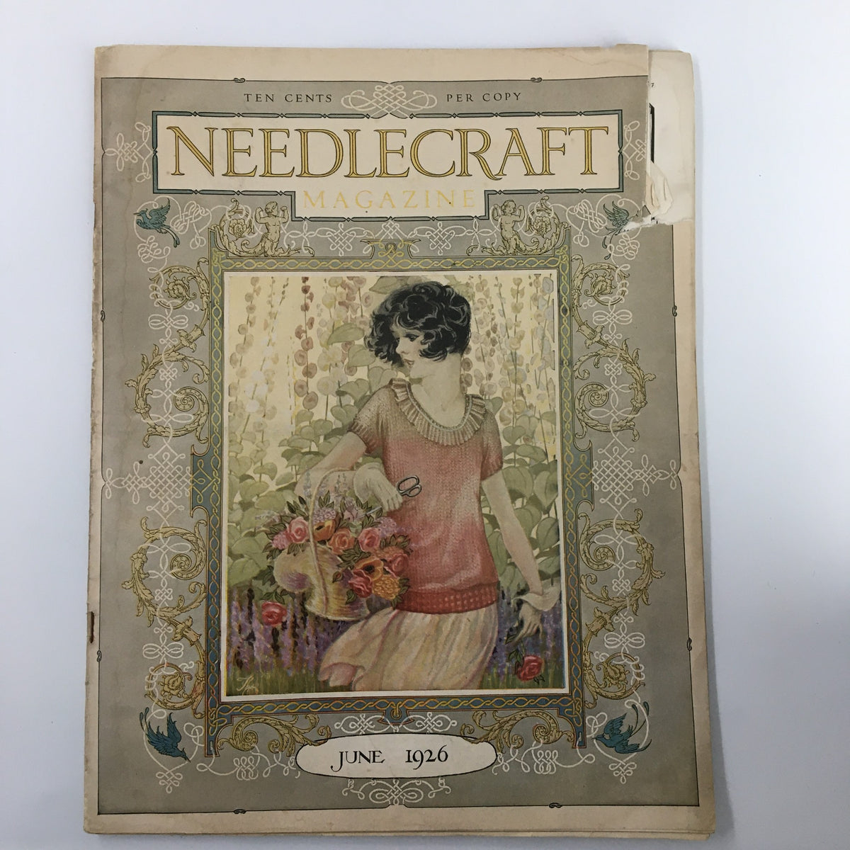 VTG Needlecraft Magazine June 1926 cover featuring a vintage illustration of a woman holding flowers, showcasing intricate border designs and typography.