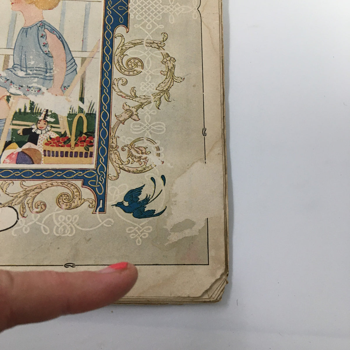 Close-up of the corner of VTG Needlecraft Magazine July 1926 showing detail of the cover design, including a blue bird illustration and signs of vintage wear.