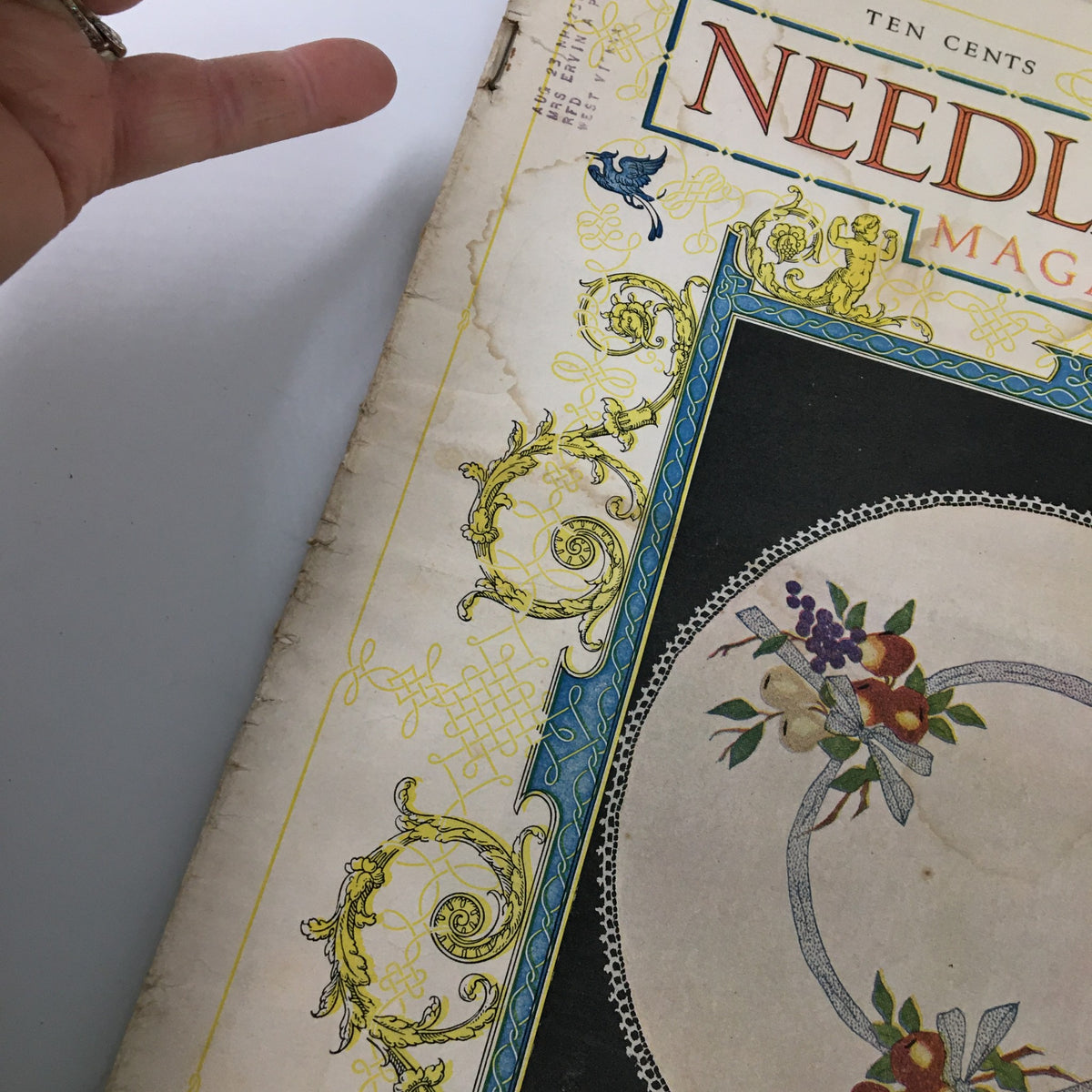 Close-up view of the top corner of VTG Needlecraft Magazine December 1921, showcasing the ornate detailing and the title 'Needlecraft Magazine'.