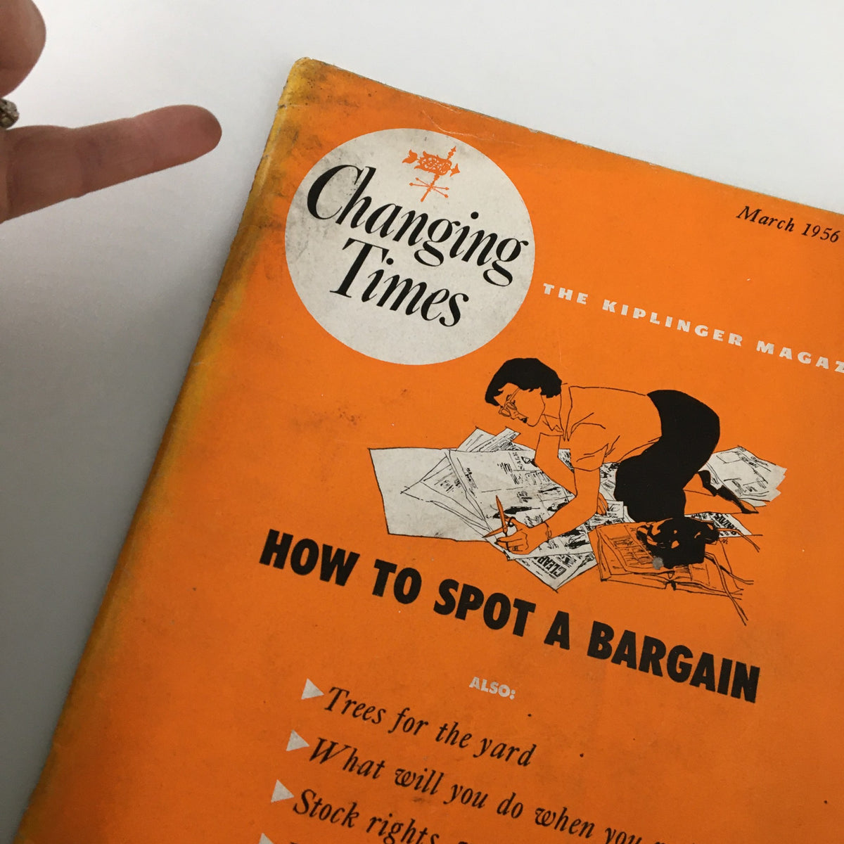 Cover of VTG Changing Times Magazine March 1956 featuring the title and an illustration of a woman analyzing stock papers with the headline 'How to Spot a Bargain'.
