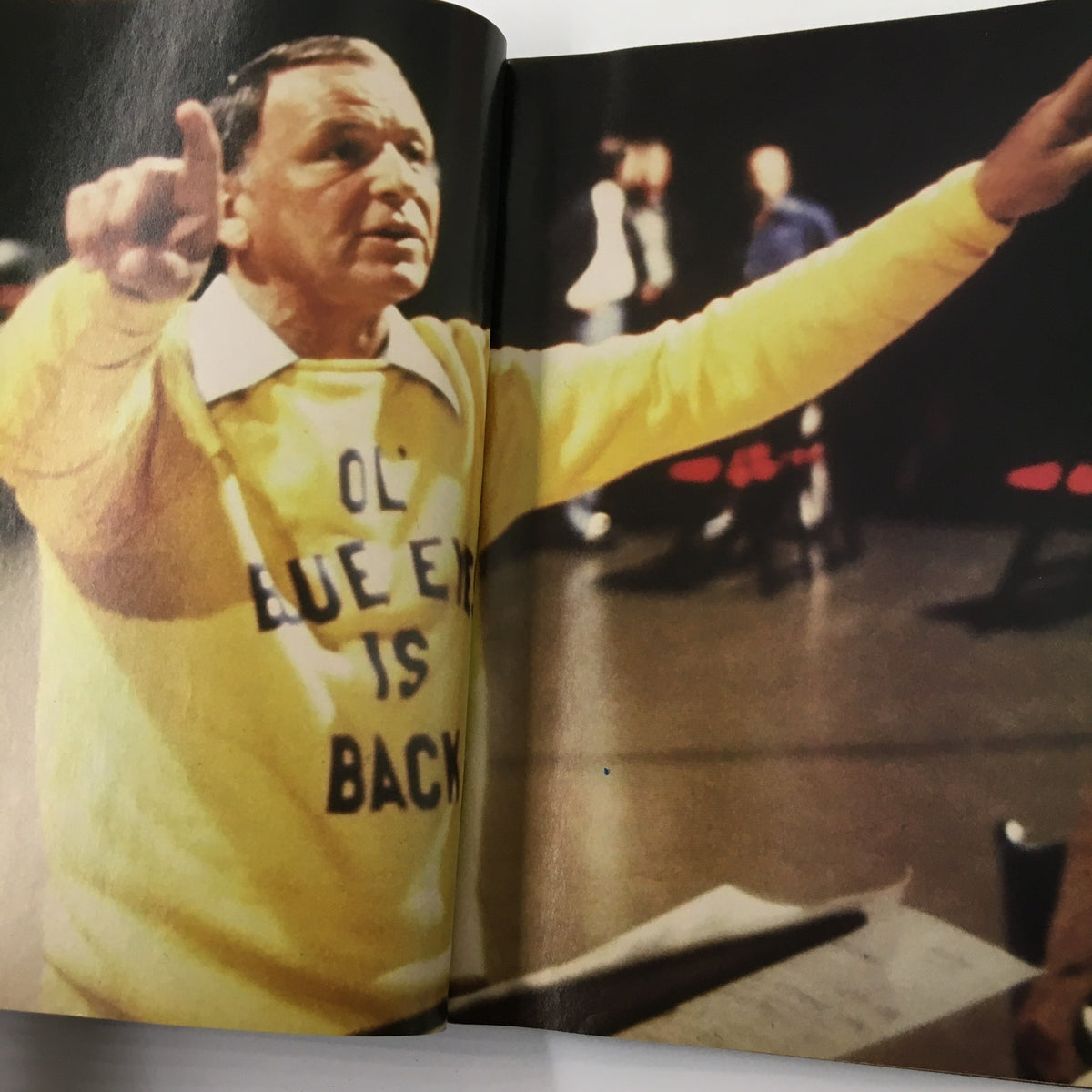 Frank Sinatra in a yellow sweater at a performance, captured in Luxury Lifestyles Magazine 1998, celebrating his influence in music.