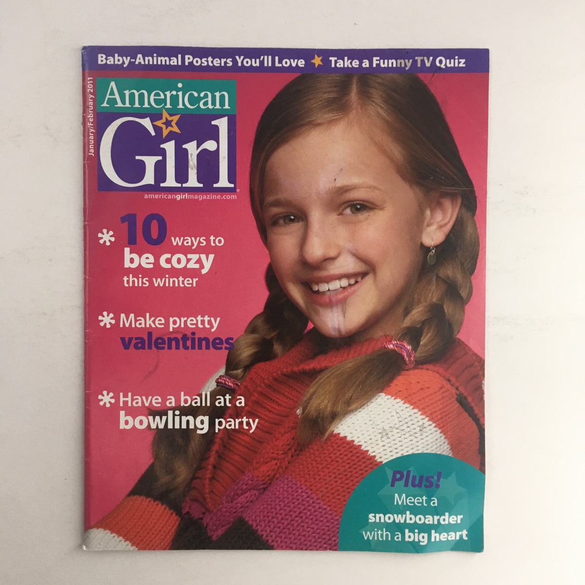 Cover of American Girl Magazine January 2011, featuring '10 ways to be cozy this winter.' The cover shows a smiling girl with braids, wearing a colorful sweater and promoting winter-themed activities.