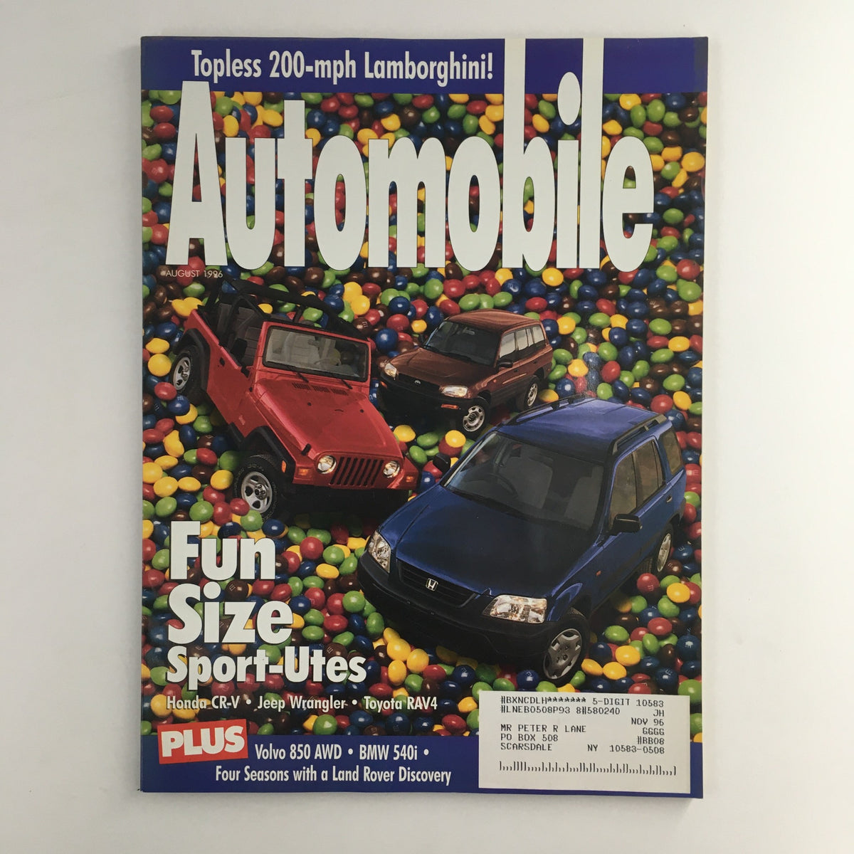 Automobile Magazine August 1996 cover featuring Honda CR-V, Jeep Wrangler, and Toyota Rav-4 amid colorful candy backdrop, highlighting vintage automotive trends.
