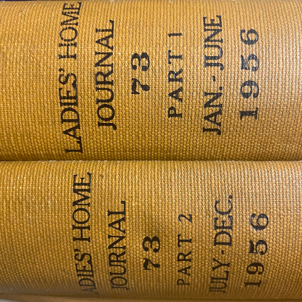 Ladies' Home Journal Library Bound Magazine 1956 Full Year January - December, a close-up of the spines of two bound volumes displaying 'Ladies Home Journal' title, part numbers, and publication dates.