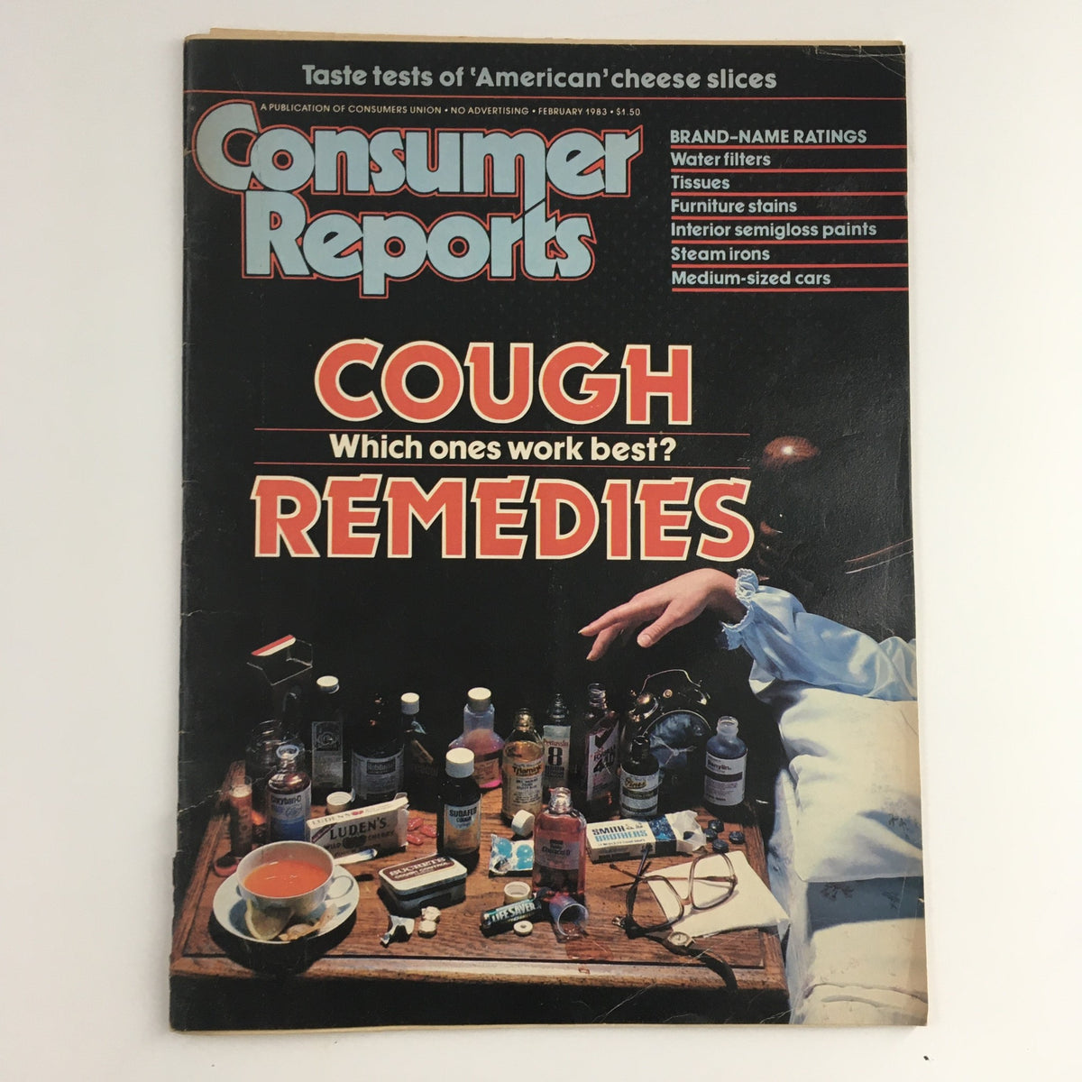 Cover of Consumer Reports Magazine from February 1983 featuring a taste test of 'American' cheese slices, with a focus on cough remedies and various medicinal bottles displayed on a table.
