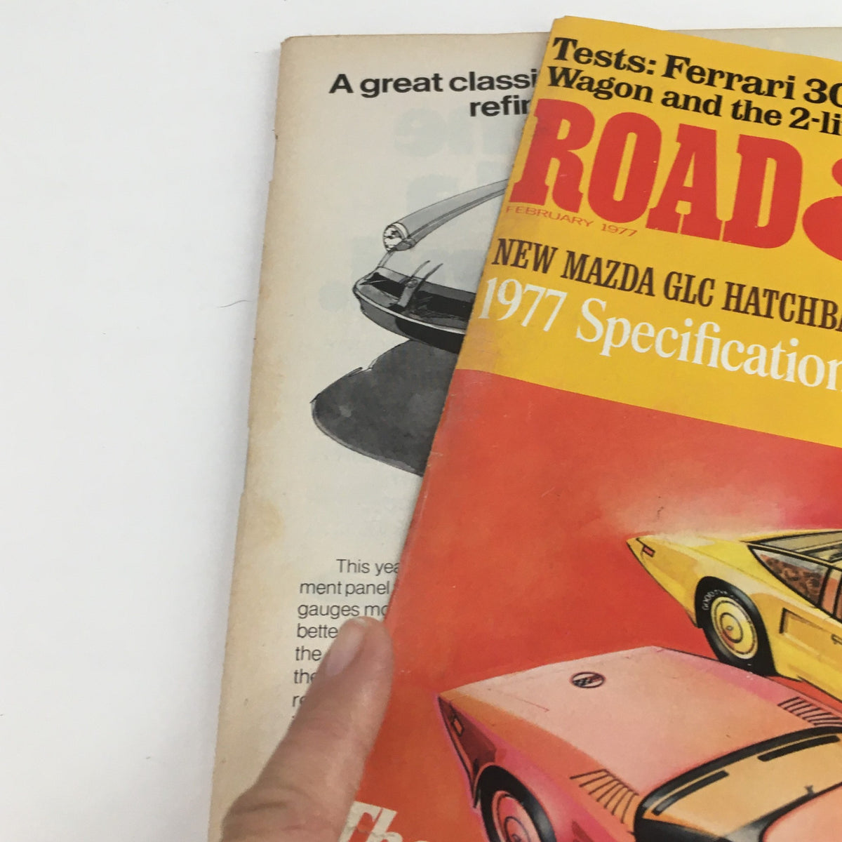 Close-up of Road & Track Magazine February 1977, showcasing the Mazda GLC Hatchback along with parts of the page, emphasizing vintage design and car specifications.